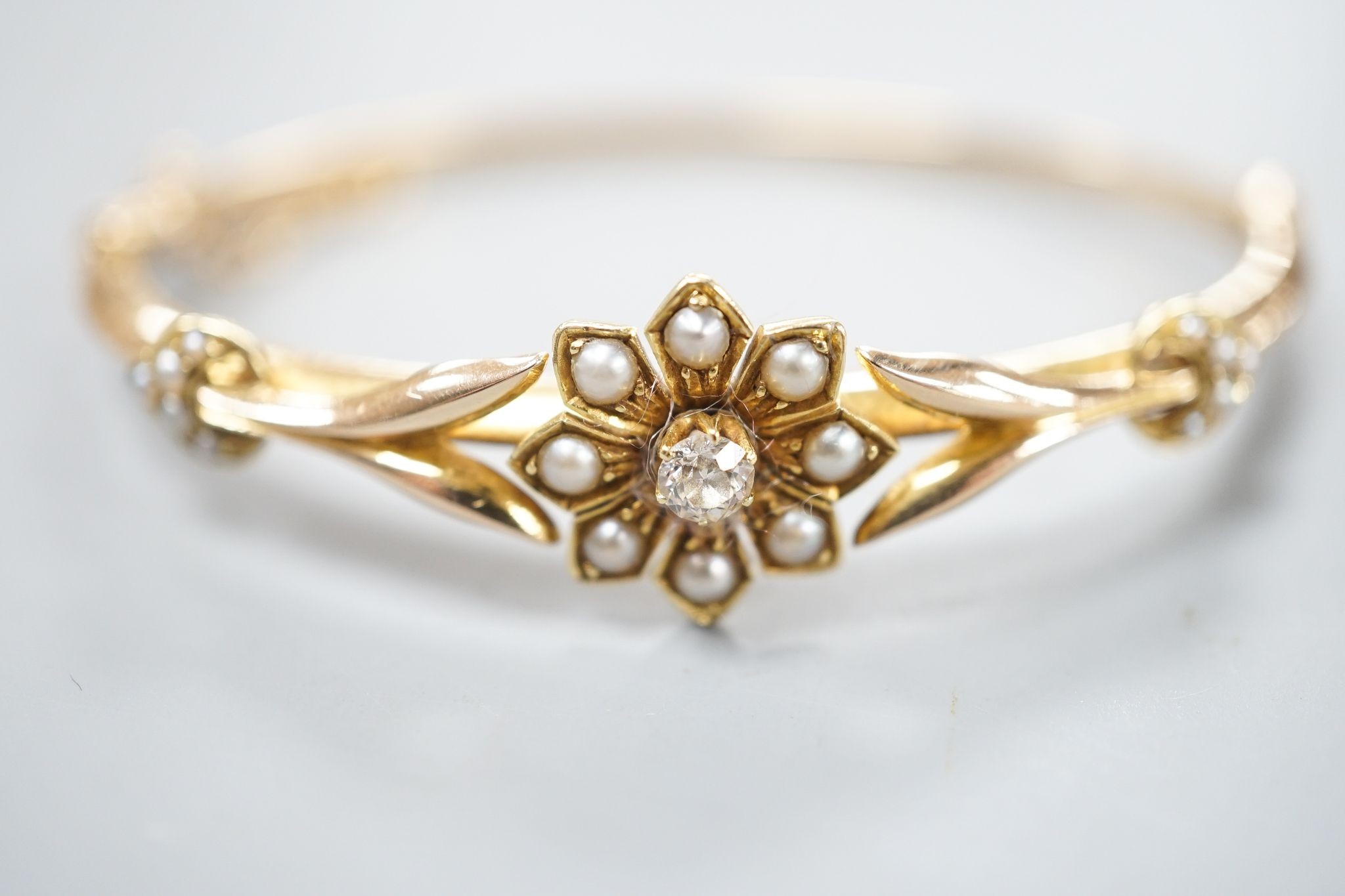 An early 20th century yellow meta diamond and seed pearl set hinged bangle, gross 9.5 grams.